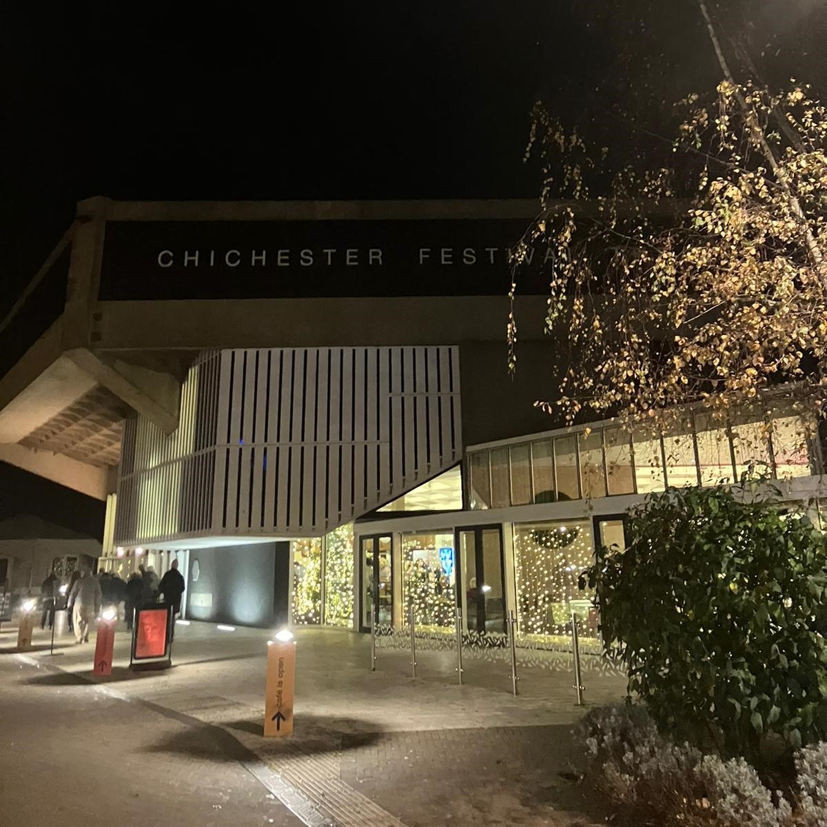 Outside of Chichester Festival Theatre at night, which has bright Christmas lights