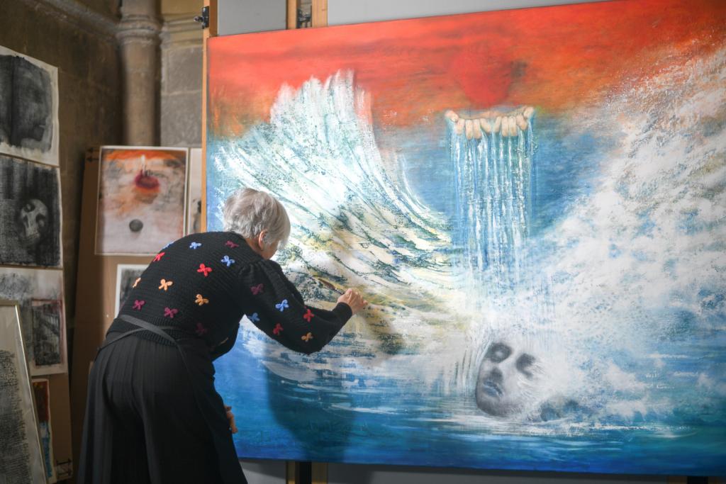 Anne Grebby paints white feather strokes, depicting the Baptism of Christ using blue and red colours.